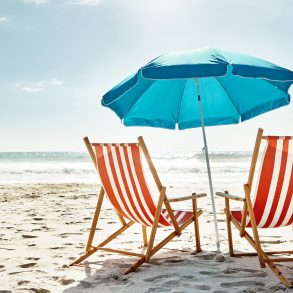 Still life shot of two deck chairs under an umbrella on the beach