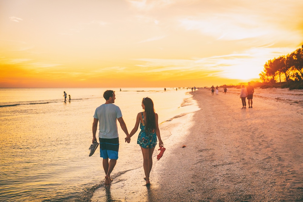 Beach summer beach people lifestyle happy couple enjoying sunset walk on Shelling beach famous tourist destination on the southwest coast of Florida -Gulf of Mexico. Sanibel Island, Florida. See Less 
